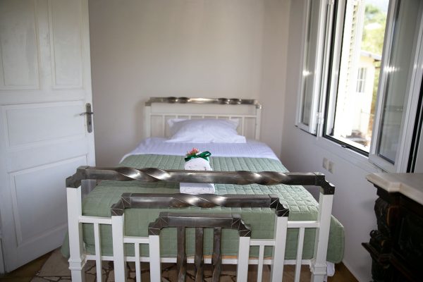 Hidden Gem Kefalonia (House Rental) a bed with a green blanket and a white bed frame