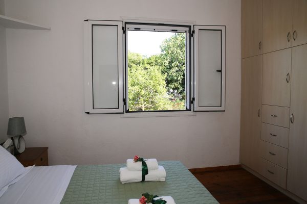 Hidden Gem Kefalonia (House Rental) a bed with a green blanket and a white pillow