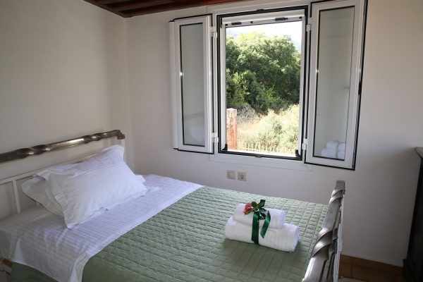 Hidden Gem Kefalonia (House Rental) a bed with a green blanket and white sheets