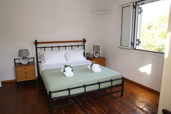 Hidden Gem Kefalonia (House Rental) a bed with a green blanket and white sheets