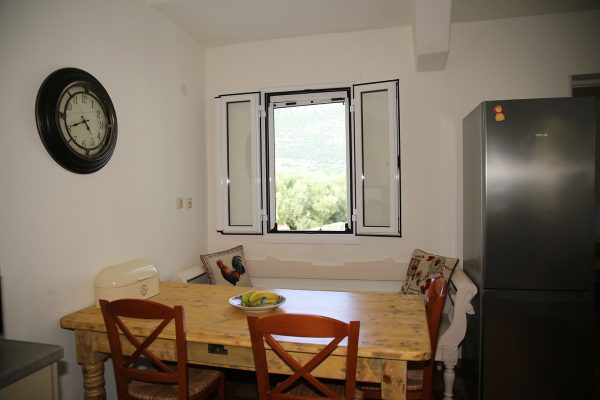 Hidden Gem Kefalonia (House Rental) a kitchen with a table and chairs and a clock