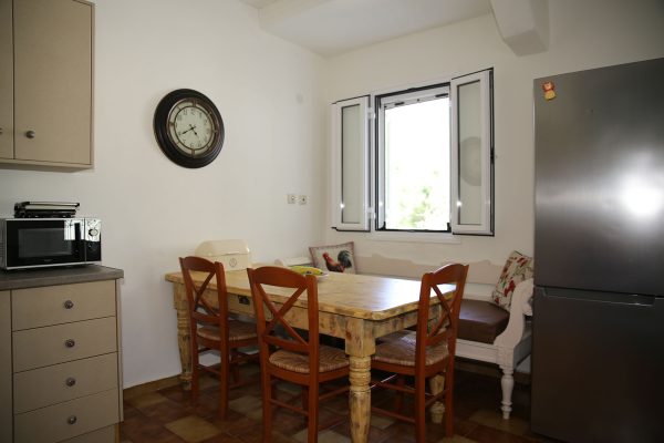 Hidden Gem Kefalonia (House Rental) a kitchen with a table and chairs and a clock